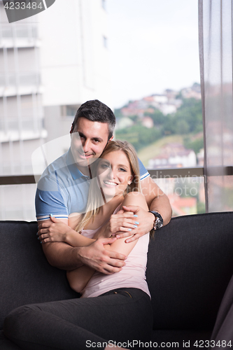 Image of young handsome couple hugging on the sofa