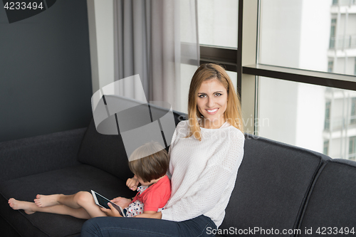 Image of mother and her cute little daughter are using a tablet