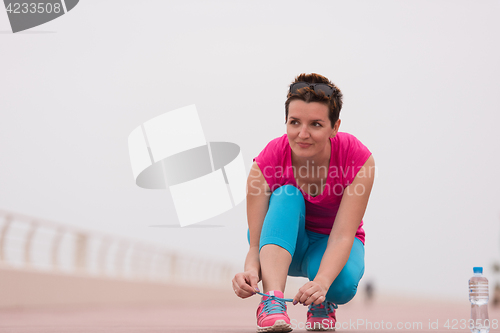 Image of Young woman tying shoelaces on sneakers