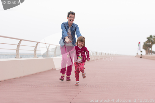 Image of mother and cute little girl on the promenade by the sea