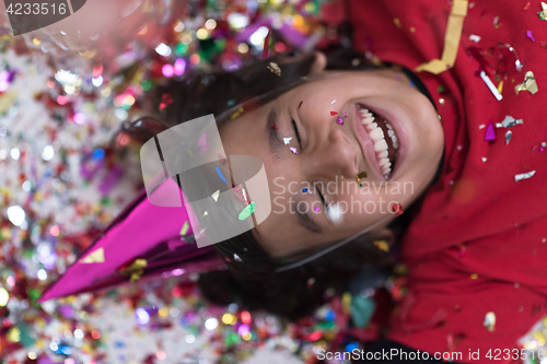 Image of kid blowing confetti while lying on the floor