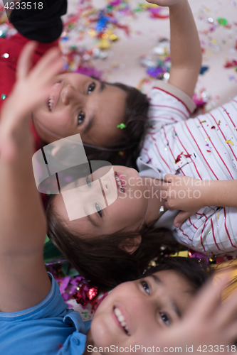 Image of kids  blowing confetti while lying on the floor