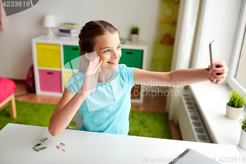Image of happy girl with smartphone taking selfie at home