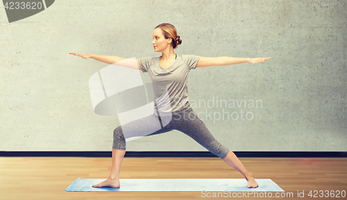 Image of woman making yoga warrior pose on mat