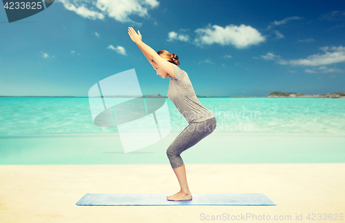 Image of woman making yoga in chair pose on mat