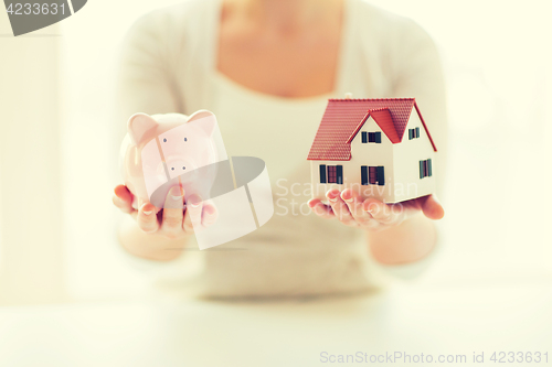 Image of close up of woman with house model and piggy bank