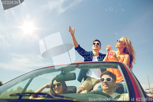 Image of friends driving in car and blowing bubbles