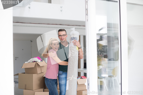 Image of couple carrying a carpet moving in to new home