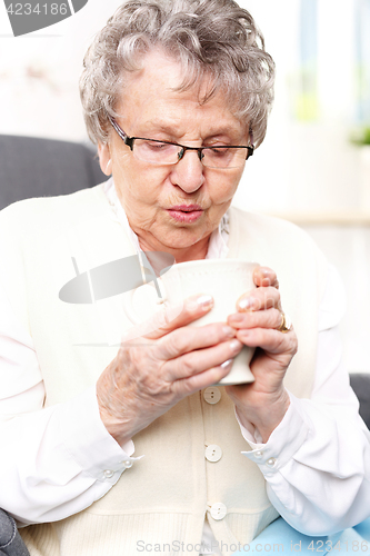 Image of Grandma&#39;s first aid kit, an infusion of herbs. Mature woman resting on a chair with a cup of brew with herbs