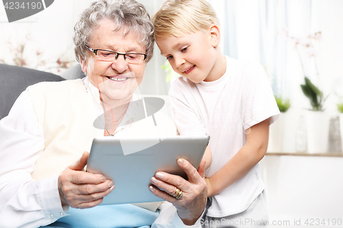 Image of Family, grandmother with grandson. Grandmother with grandson playing on the tablet.