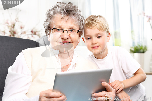 Image of Grandmother with grandson playing on the tablet.