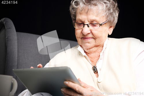 Image of Older woman with a tablet. Retired, entertainment on the Internet