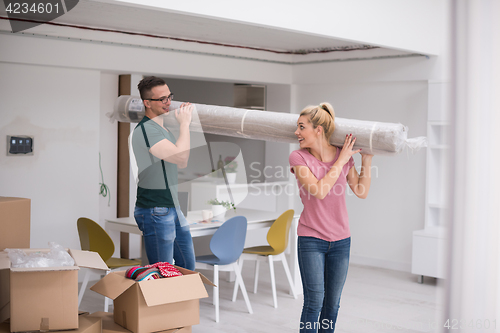 Image of couple carrying a carpet moving in to new home