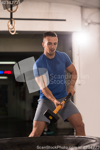 Image of man workout with hammer and tractor tire