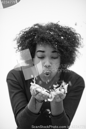 Image of African American woman blowing confetti in the air