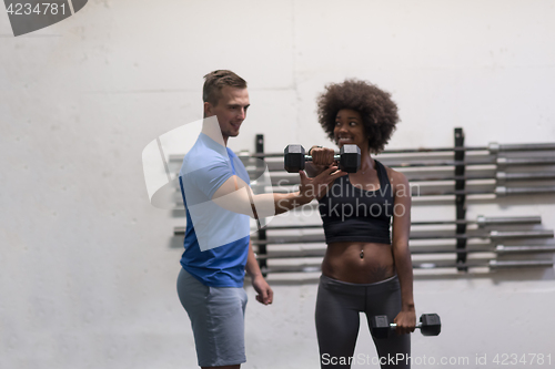 Image of black woman doing bicep curls with fitness trainer