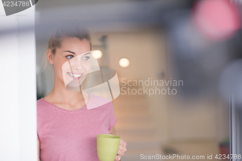 Image of young woman drinking morning coffee by the window