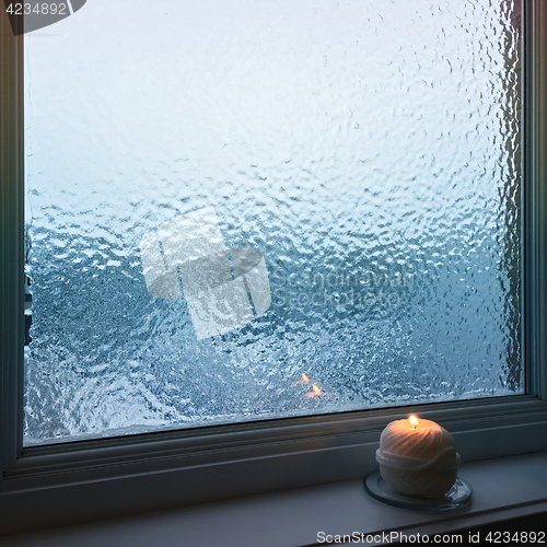 Image of Blue frosted window and cozy candlelight