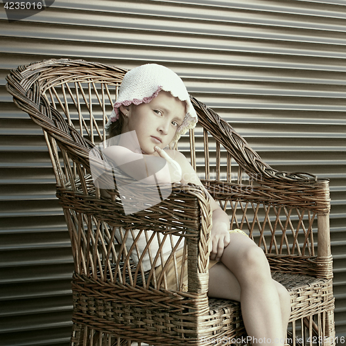 Image of Beautiful small girl seating in wicker chair