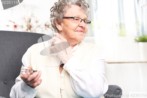 Image of Mature well groomed woman perfumes to expensive perfumes. Mature well groomed woman with perfume bottle, smelling perfume.