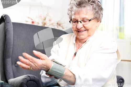 Image of Measuring blood pressure. Elderly woman measures the pressure of the home sphygmomanometer wrist.