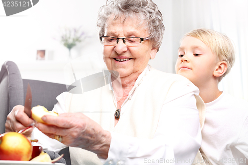 Image of Grandmother looks after the child. Grandmother to grandchild picks an apple peel