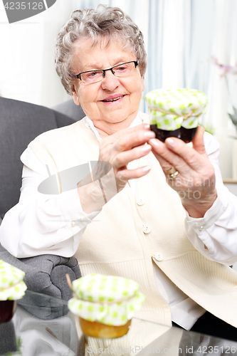 Image of Grandma prepares komfitury in jars. Grandma&#39;s preserves, delicious jams.