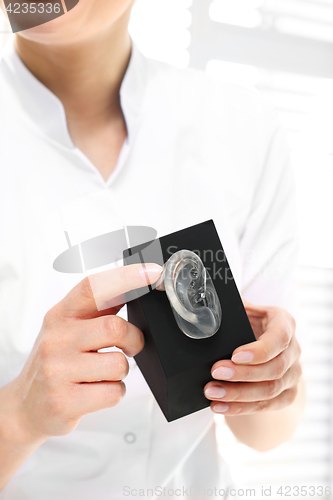 Image of Plastic ears. Female surgeon with silicone cast of the ear.