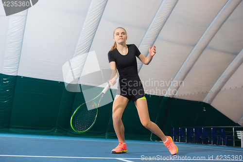 Image of The young girl in a closed tennis court with ball