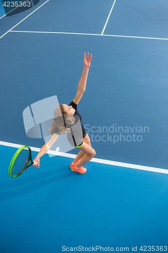 Image of The young girl in a closed tennis court with ball