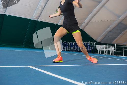 Image of The young girl in a closed tennis court with ball