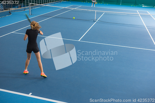 Image of The young girl in a closed tennis court with ball