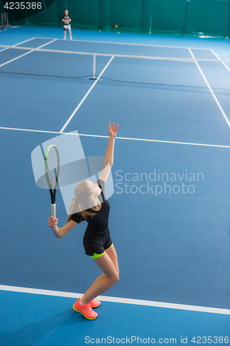 Image of The young girl in a closed tennis court with ball