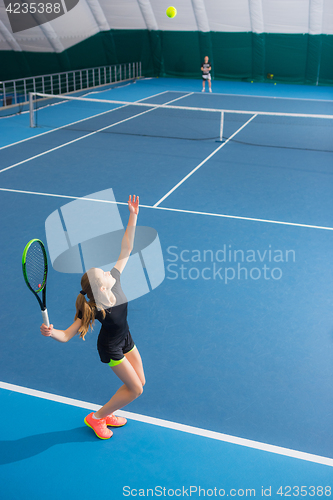 Image of The young girl in a closed tennis court with ball