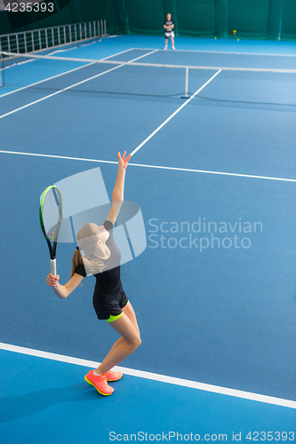 Image of The young girl in a closed tennis court with ball