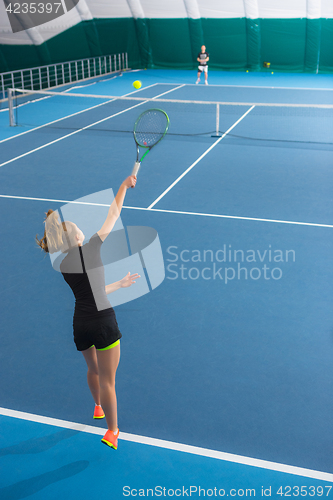 Image of The young girl in a closed tennis court with ball