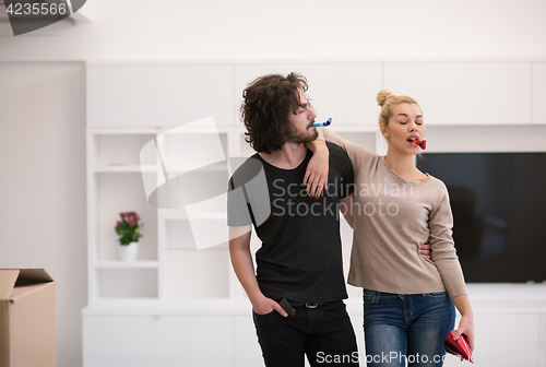 Image of couple in party hats blowing in whistle