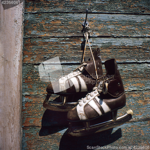 Image of vintage pair of mens  ice skates hanging on a wall