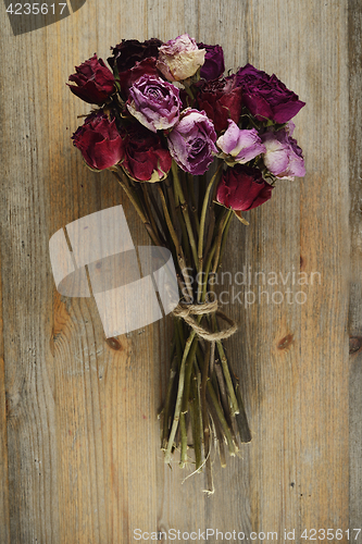 Image of bouquet of dried roses on a wooden background