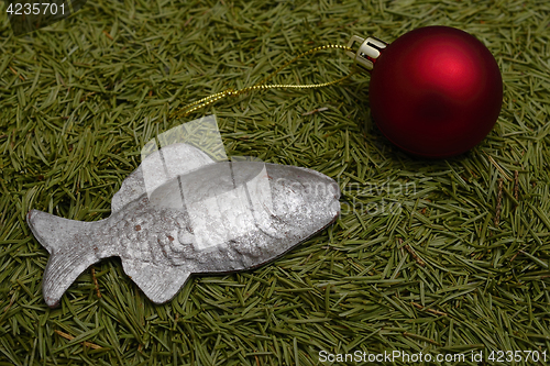 Image of Christmas ball and fish on green fur-tree needles