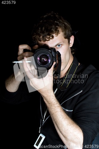 Image of The young man - photographer behind work. Isolated on a black ba