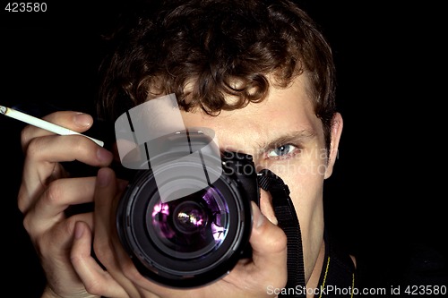 Image of The young man - photographer behind work. Isolated on a black ba