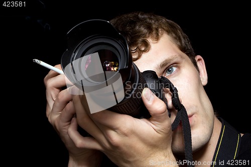 Image of The young man - photographer behind work. Isolated on a black ba