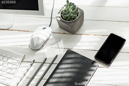 Image of Office desk table with computer, supplies and phone