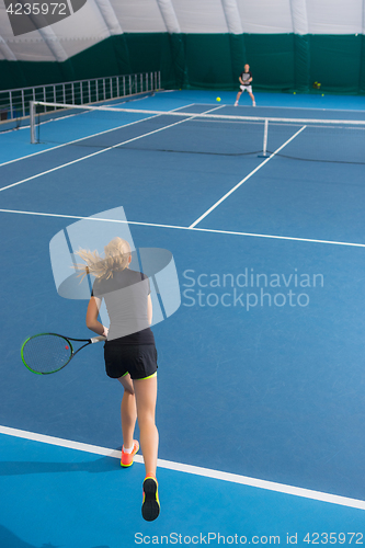 Image of The young girl in a closed tennis court with ball