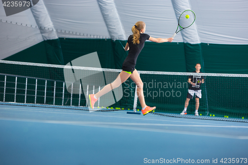 Image of The young girl in a closed tennis court with ball