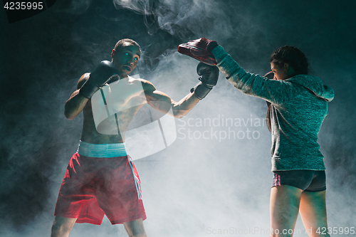 Image of Handsome Afro American boxer with bare torso is practicing punches with a partner at the fight club