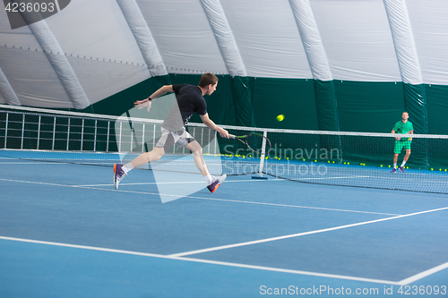 Image of The young man in a closed tennis court with ball