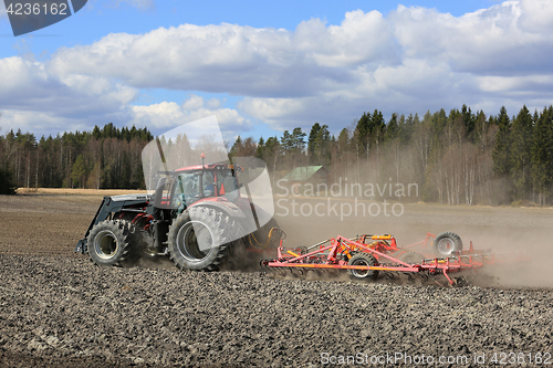 Image of Farm Tractor and Cultivator on Field at Spring