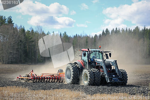 Image of Farm Tractor and Cultivator on Field at Spring